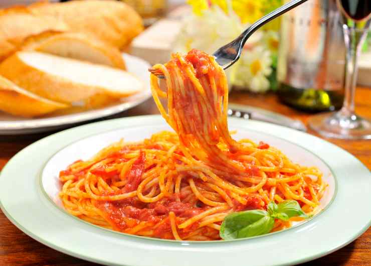 spaghetti al pomodoro fresco in un piatto con forchetta e pane